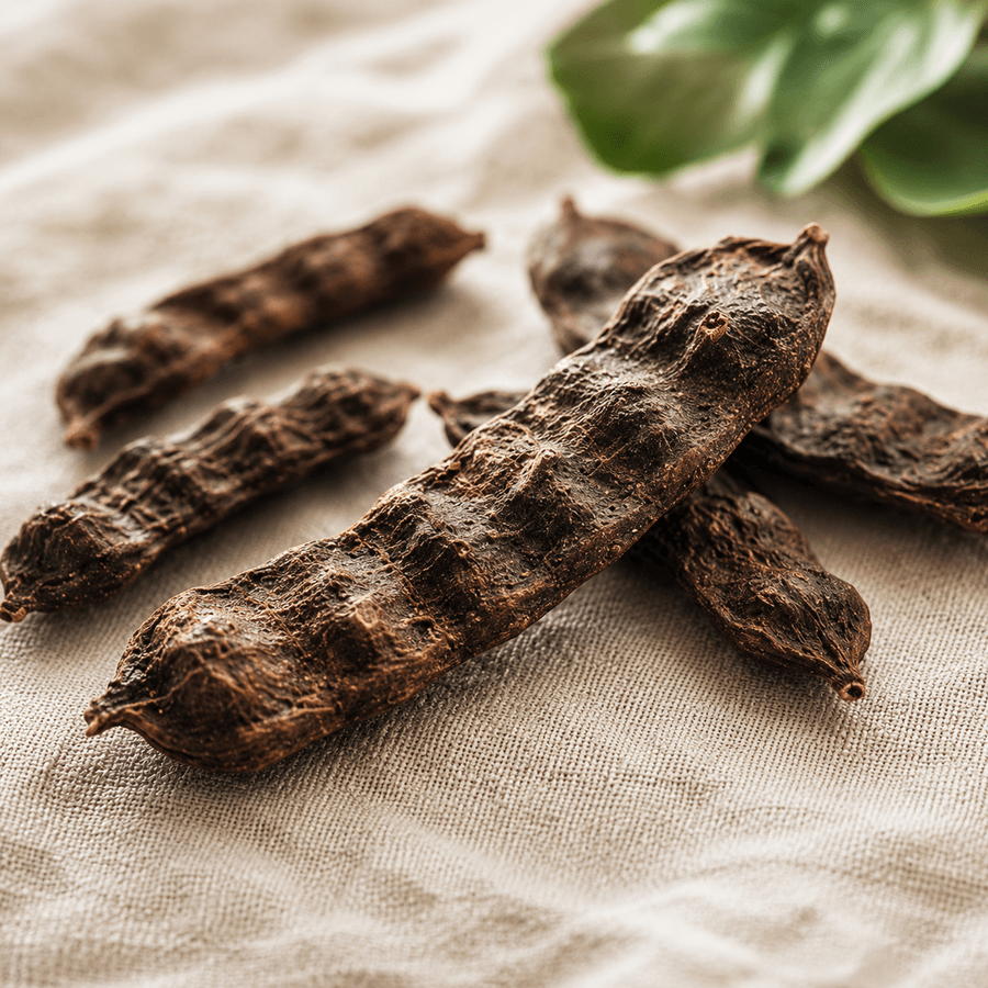 Textured brown Shikakai pods arranged on white linen with soft shadows.